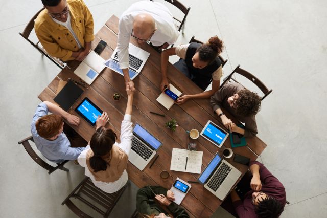 looking down on a team of people sitting arond a large table all working together