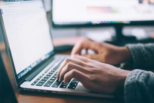 a mans hands typing on a laptop