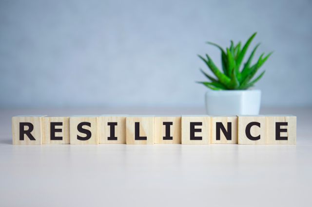 wooden clocks on a desk spelling out the word resilience which is one of our essential soft skills to master