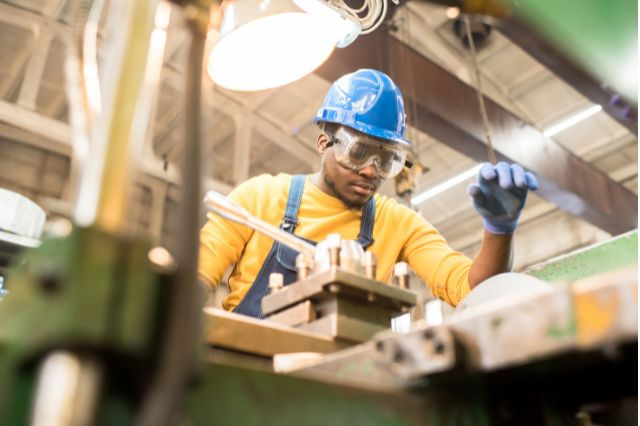 A young man in a hard hat working in a manufacturing warehouse