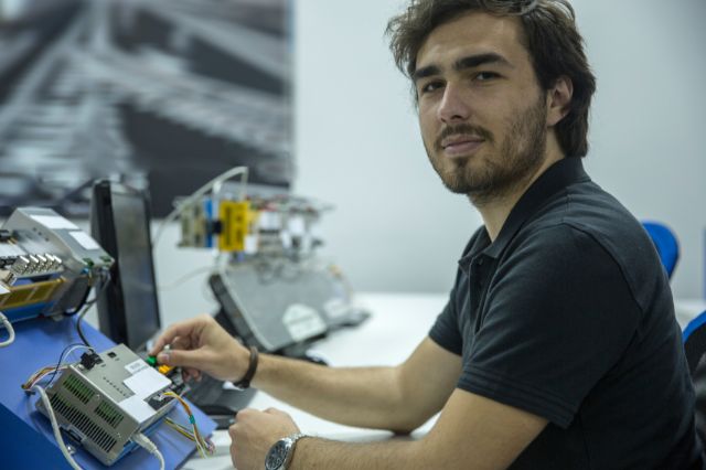 an electronics engineer working at a work desk covered in electronics components