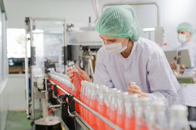 A woman wearing a hair net inspecting products on an FMCG production line