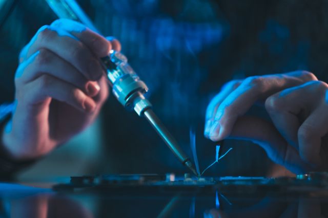 a close up of a pair of electronics engineers hands working on a circuit board