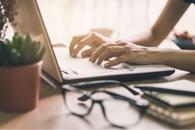 a persons hands typing on a laptop as they tailor the cv to a specific job application