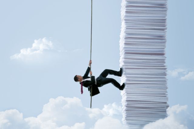a recruiter in a suit climbing a rope up the side of a tall tower of paperwork
