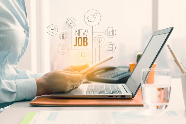 a man holding a phone over his laptop while working on optimising his linkedin profile