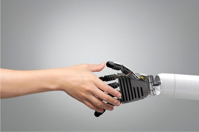 a human hand and a robot hand shaking hands to represent using AI to assist in your job search