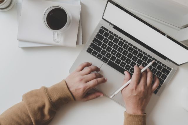 looking down at a pair of hands typing on a keyboard as someone uses AI to assist in their job search