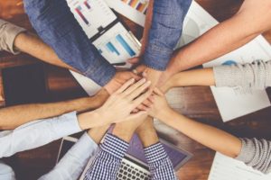 a team of people putting their hands into a team circle