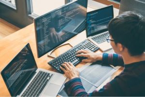 An embedded software engineer coding on 3 laptops at the same time