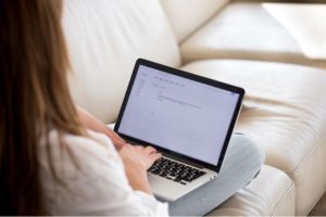 a woman sitting on a sofa with a laptop on her lap writing a cover letter