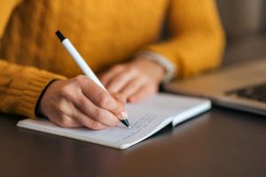 a man sitting at a desk writing a cover letter into a notepad