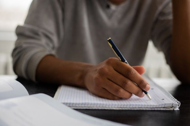 a man sitting at a desk writing a cover letter in a notepad