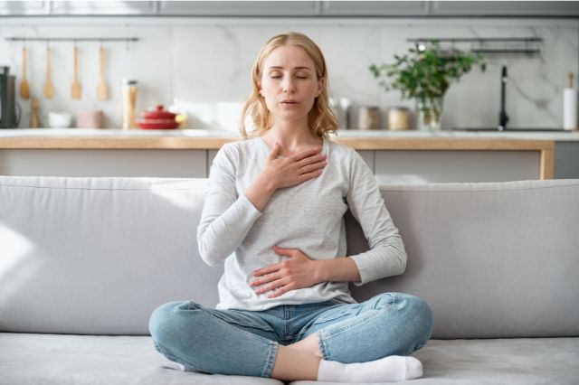 a woman sitting on a sofa doing some breahing exercises to help her cope with interview nerves