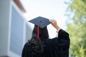 a young graduate holding her graduation cap and facing away from the camera